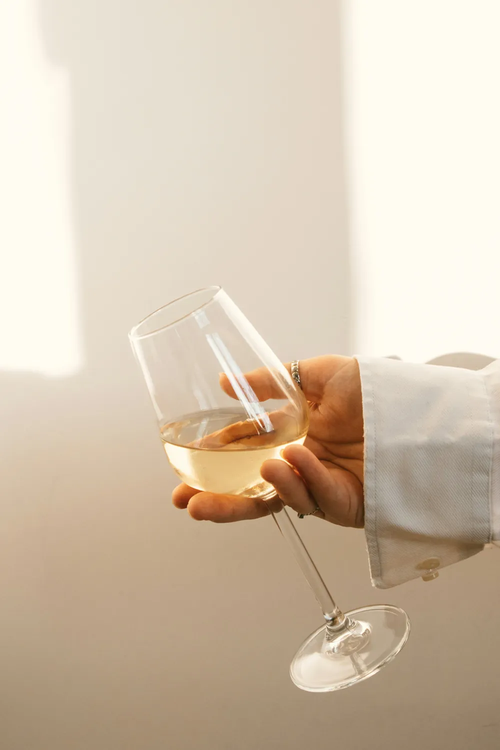 Main tenant un verre de vin blanc